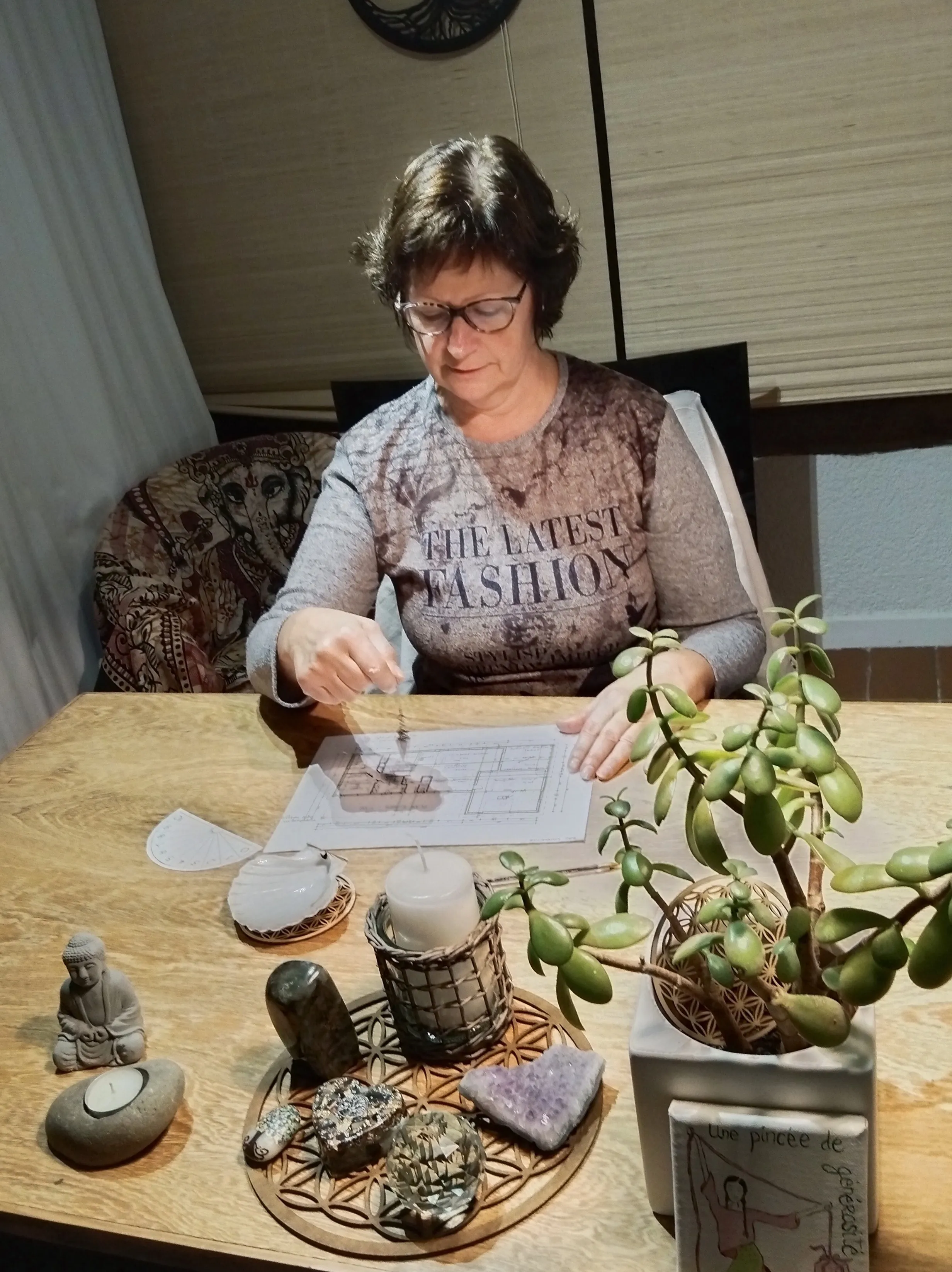 Sylvie Tauzin pratiquant la radiesthésie avec un pendule sur un plan